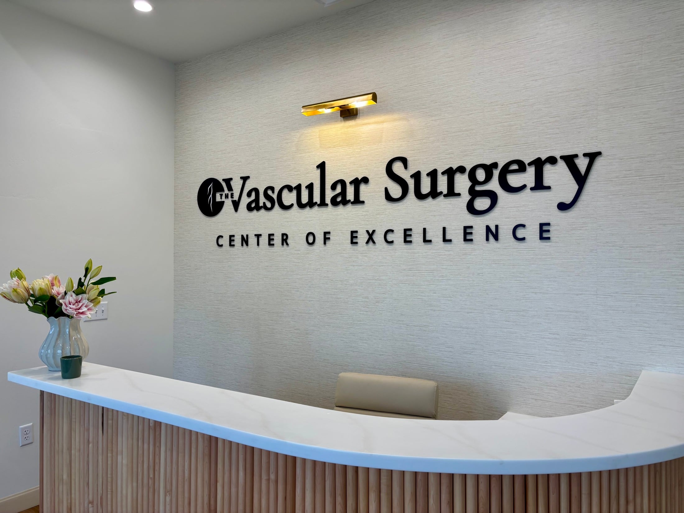 The reception desk and wall sign inside The Vascular Surgery Center of Excellence
